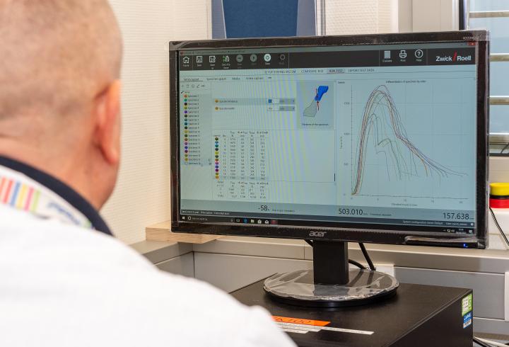View of man in front of computer screen displaying line graph