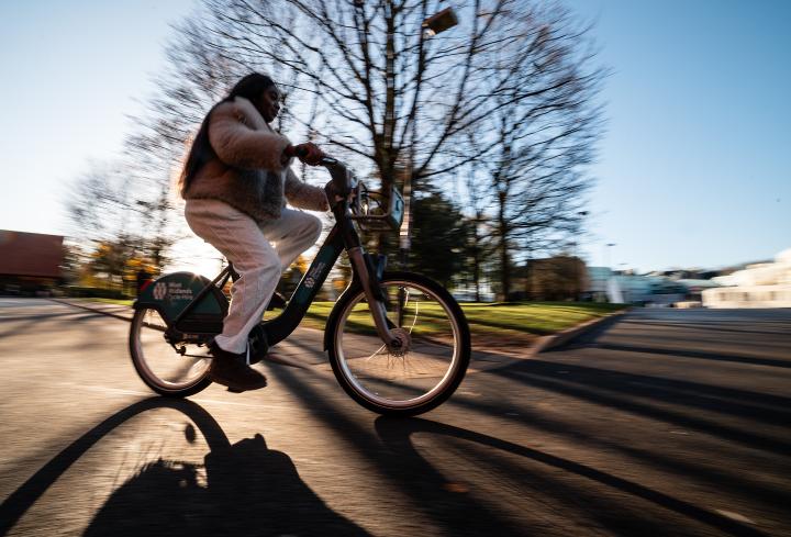 A student cycles outside Senate House, the sunny background is a blur
