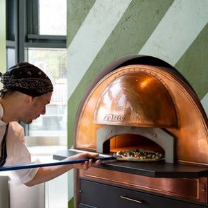 Man putting pizza in pizza oven