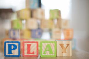 Image of 4 children's building blocks, spelling 'PLAY'