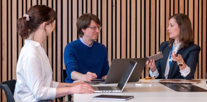 Three staff members on laptops sat around a desk