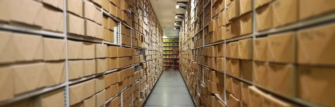 Photograph of one of the Modern Records Centre's strongrooms, looking through the aisle past lots of acid free boxes on shelves.