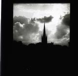 Silhouette of church spire with well lit clouds