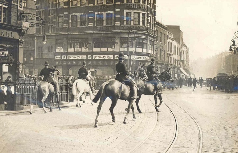 Police officers on horses with batons drawn, chasing protestors in London during the General Strike.