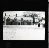 Woman walking along a snow covered street, houses in background
