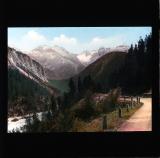 Touched-up scene of path along river towards mountain peaks, Switzerland