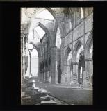 Ruins of cathedral or abbey, arches still standing but no roof. Looking towards large window.