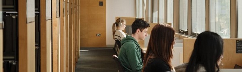 students at study desks with bookshelves behind