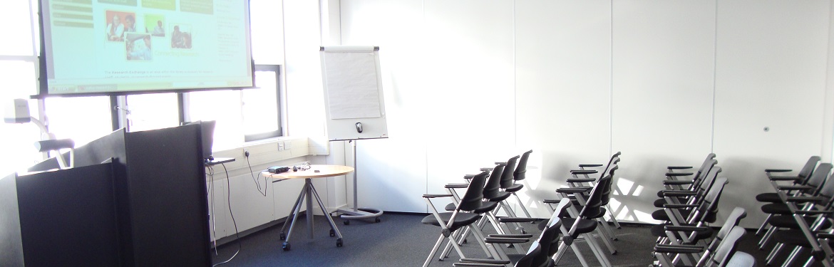 Wolfson Research Exchange seminar room with projector screen, whiteboard and rows of chairs