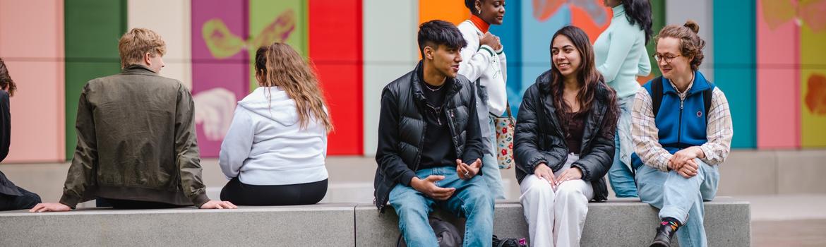a group of philosophy students sitting on a bench outside fab facing different directions and looking contemplative