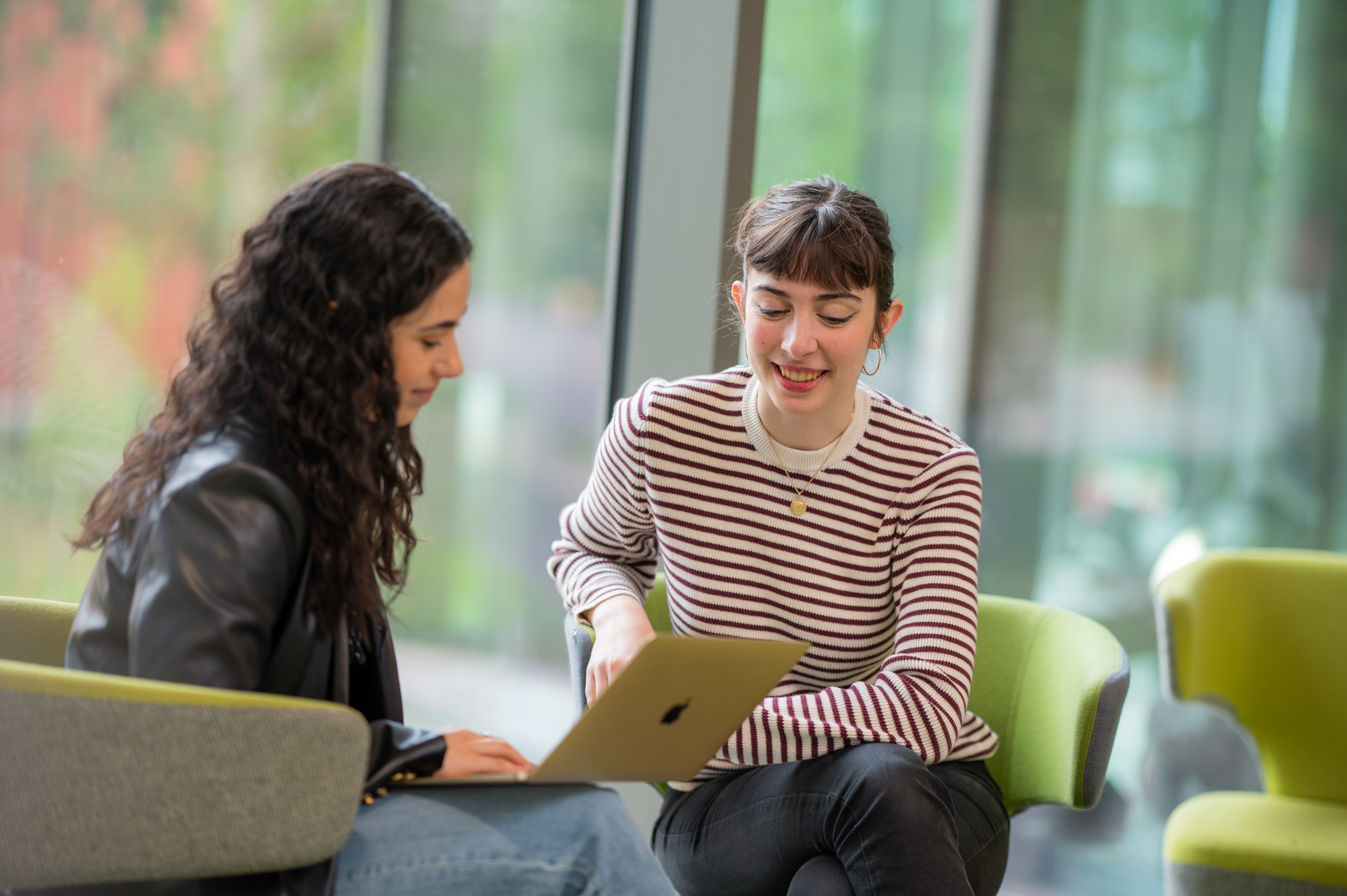 Two students discuss their research in the lobby of the Faculty of Arts Building at the University of Warwick