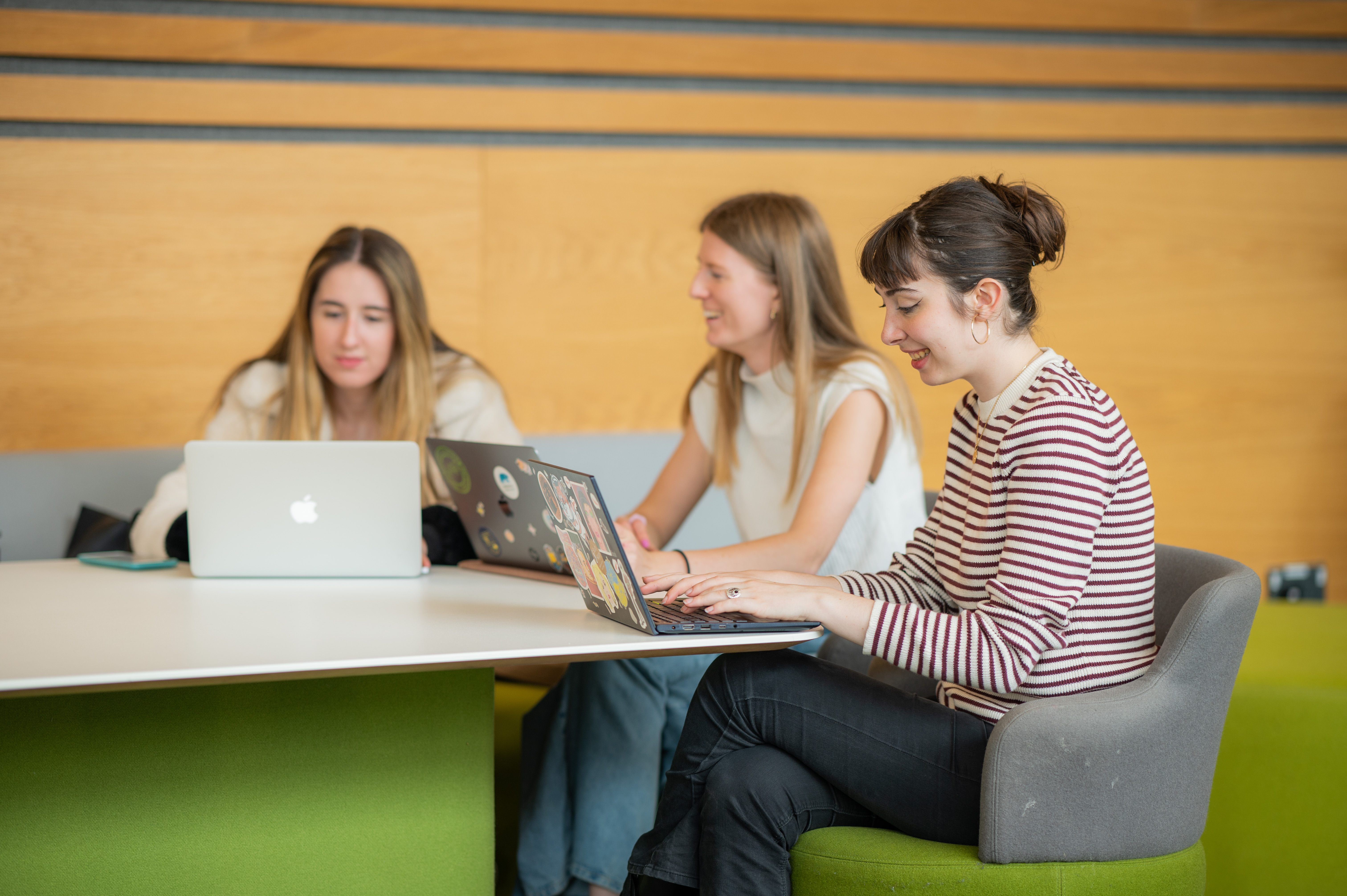 A group of three students work together on their laptops in one of the shared spaces in FAB