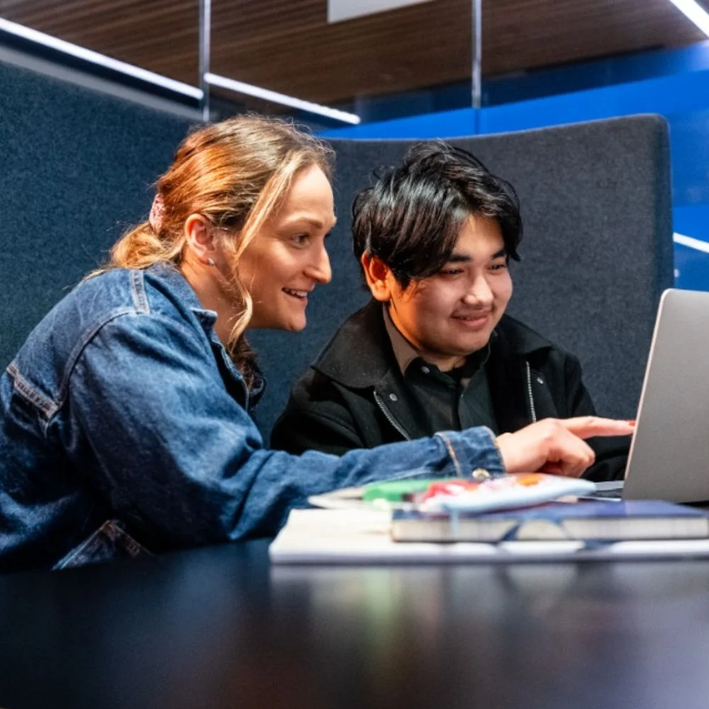 Two students working on a laptop
