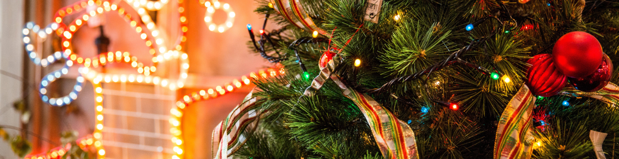 A lit Christmas tree with lights in the background