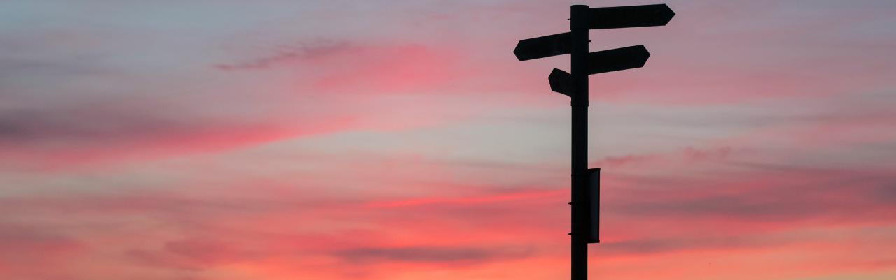 Sunset background with a directional signpost silhouette