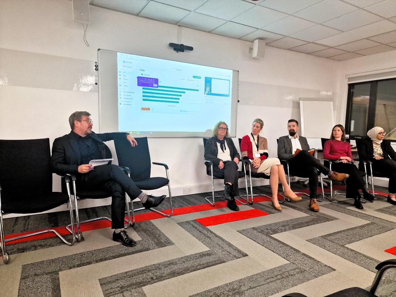 A Chair hosts a panel of five experts sat in a row