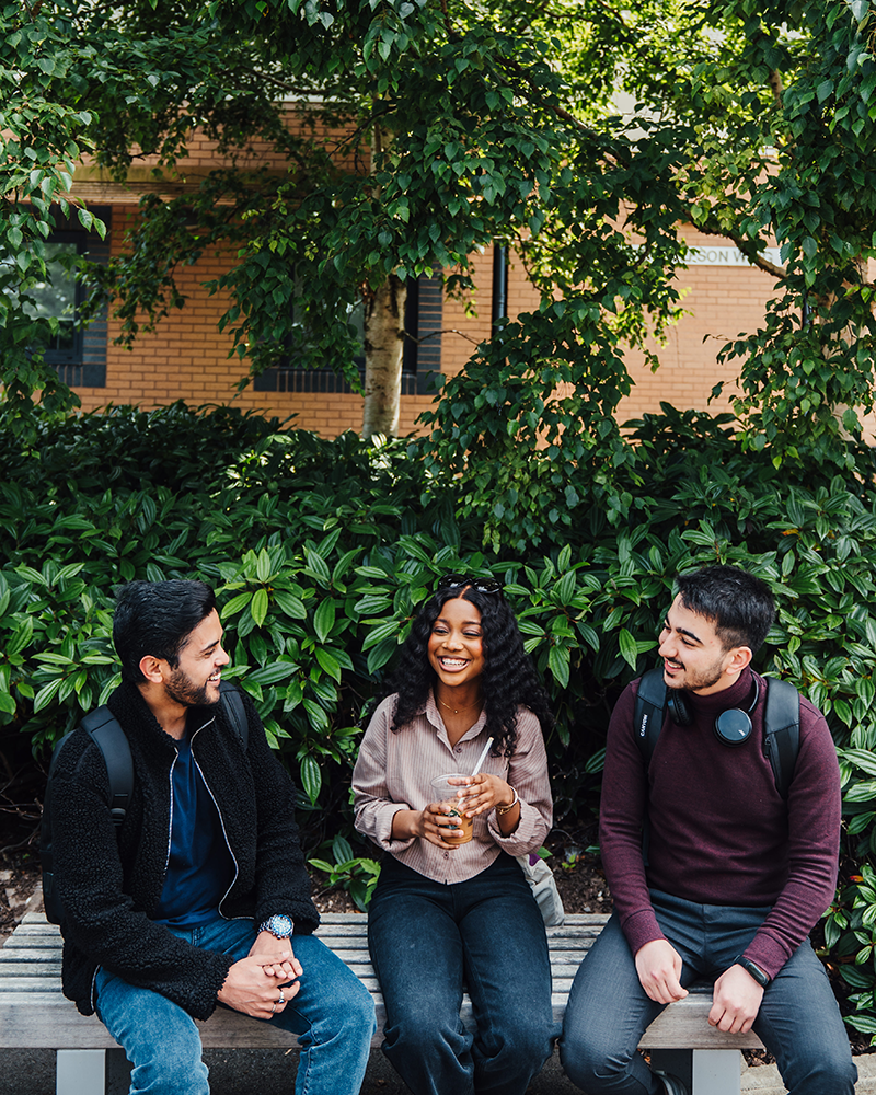 Three students sitting on a bench