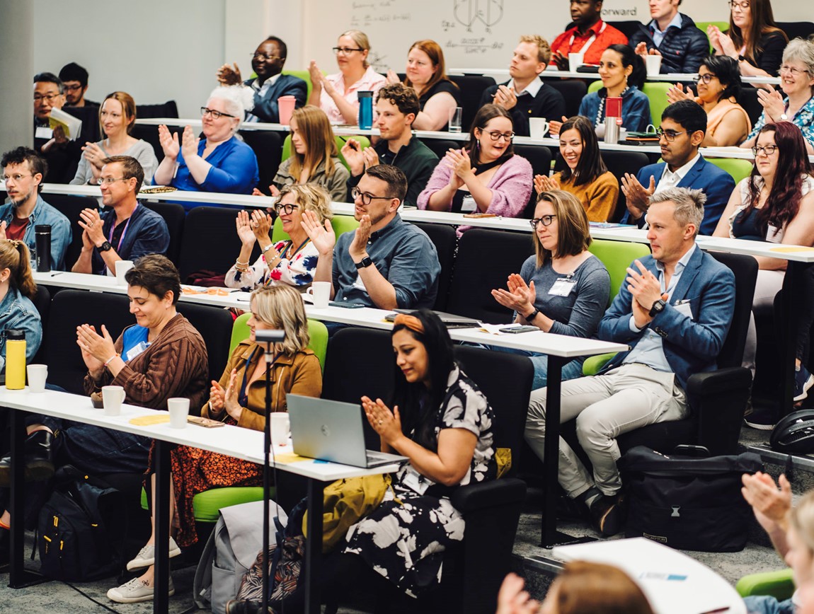 Conference attendees from 2023 clapping at the keynote speech