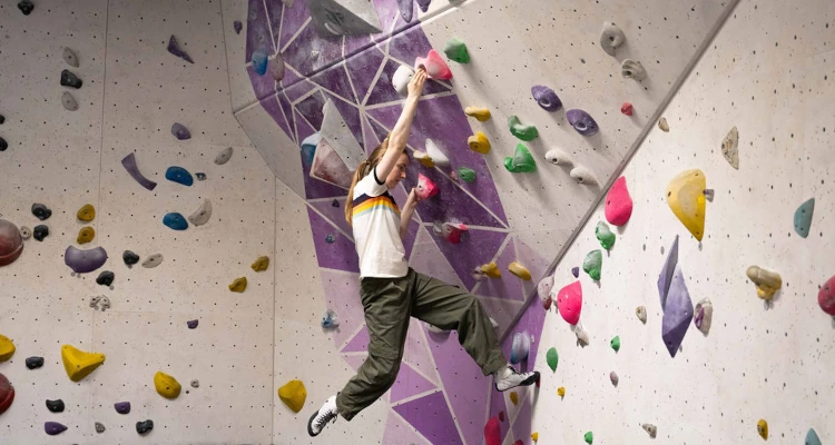 photo of a person swinging from a bouldering wall