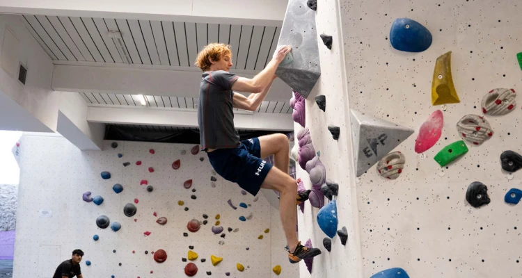 a man climbing up a bouldering wall