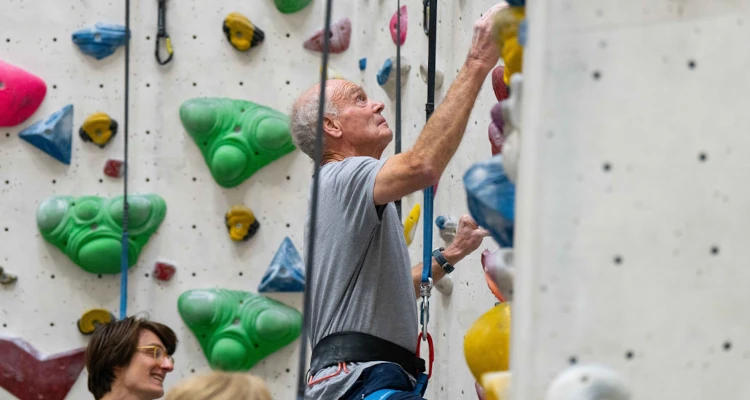 Older man climbing up a wall in the climbing centre