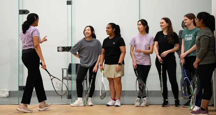 Group of people listening to a coach on a squash court