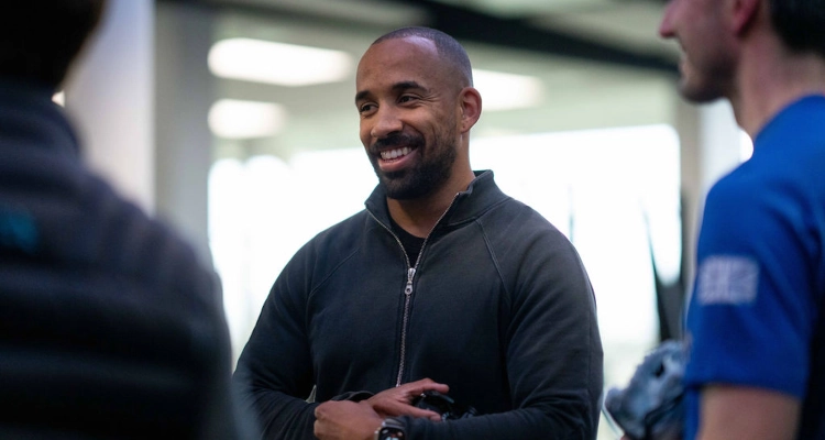 A person wearing a black zip up top engaging in conversation at the gym