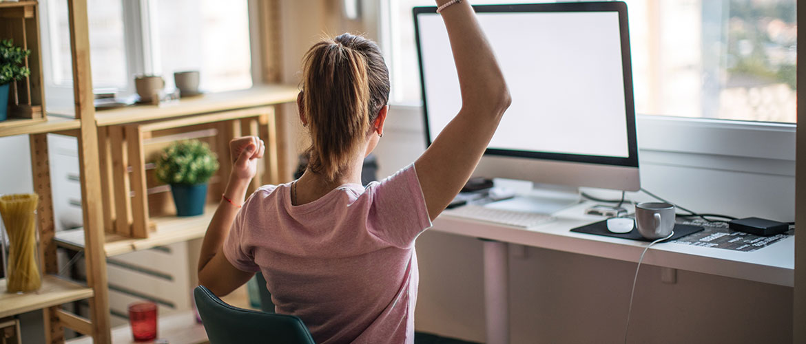 Woman doing arm stretches at her desk in front of a computer