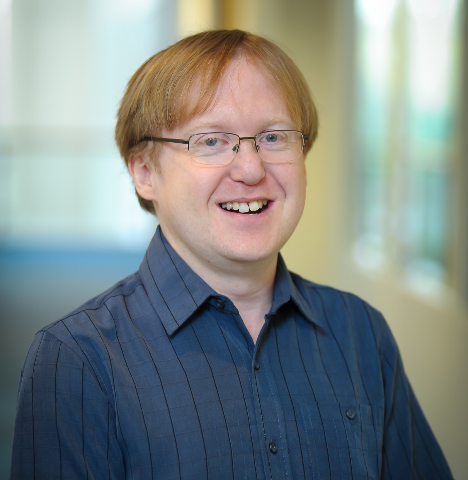 Image of a man in a blue shirt, on a blurred background