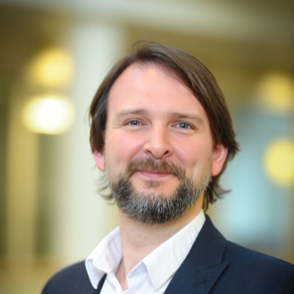 image of a man in a suit smiling with a blurred background