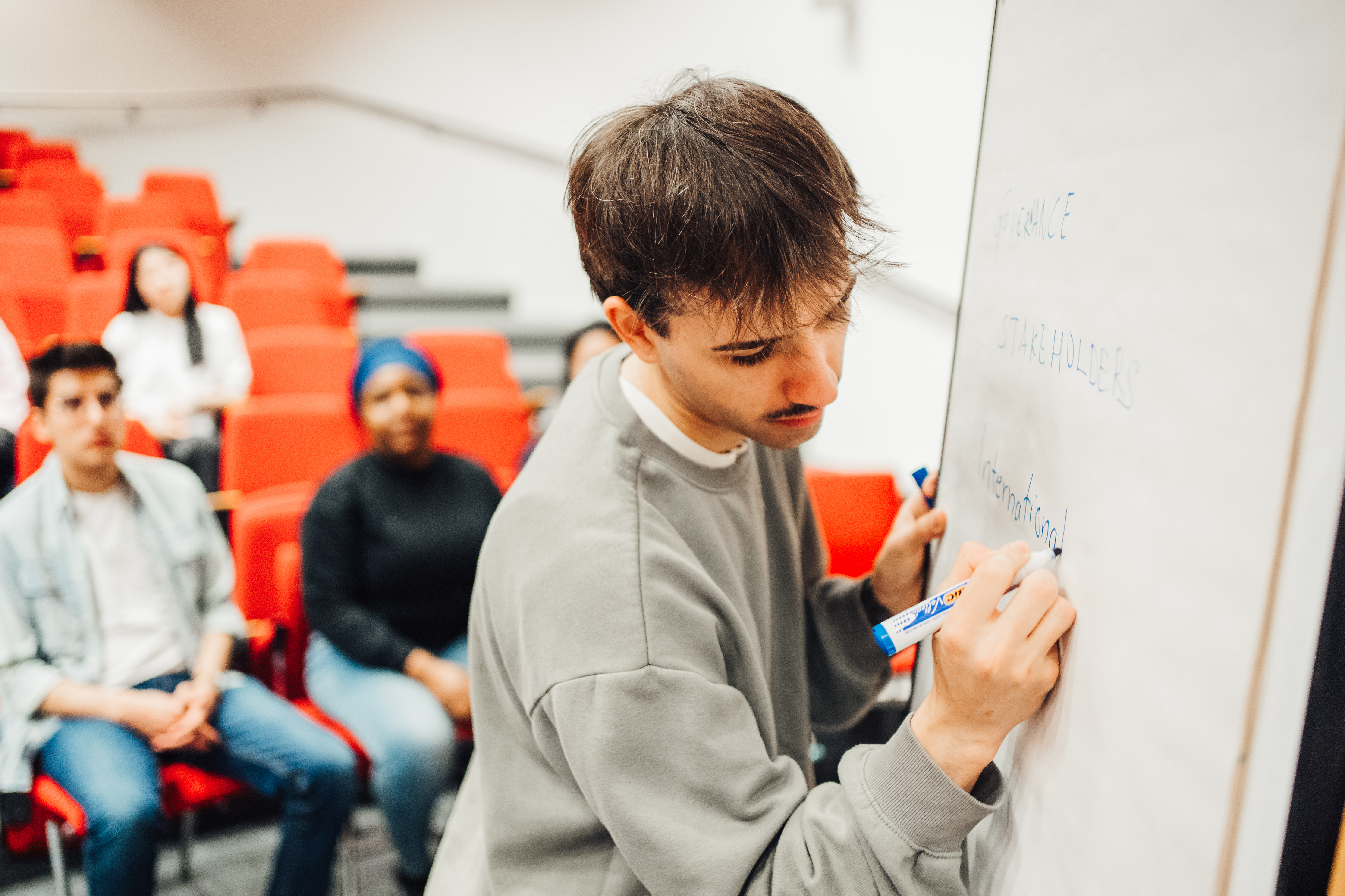 male student writing on a board