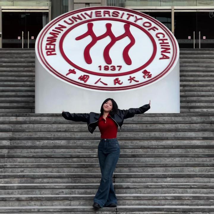 Student in front of Renmin University of China logo