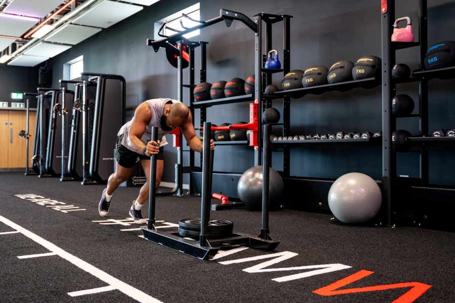 Gym user pushing weighted sled in a gym
