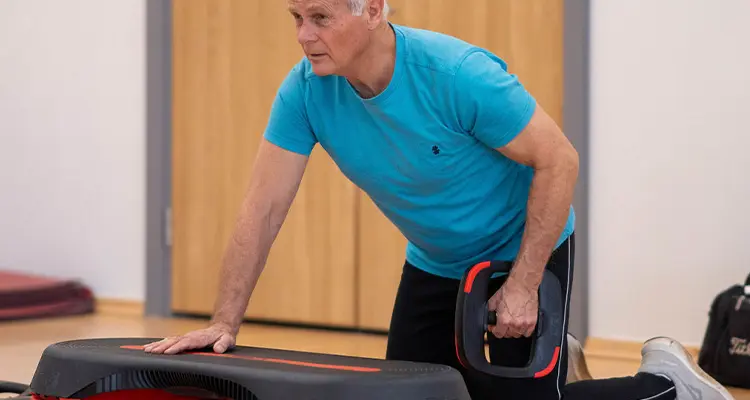 Man kneeling  in front of stepper and raising a weighted plate