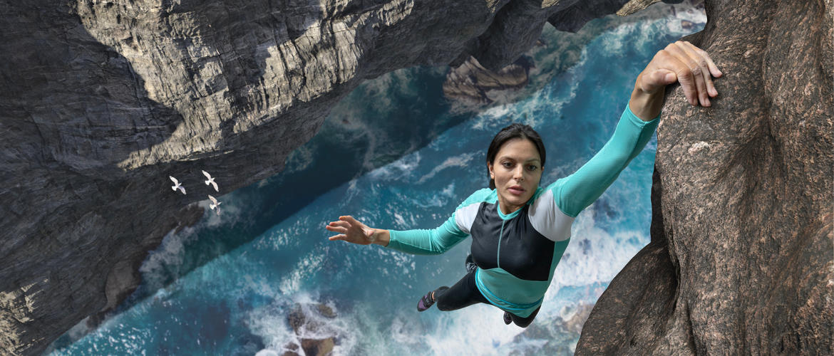 Woman hanging from rock face by finger tips