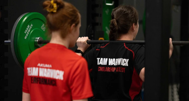 two people using a barbell with weights in the gym