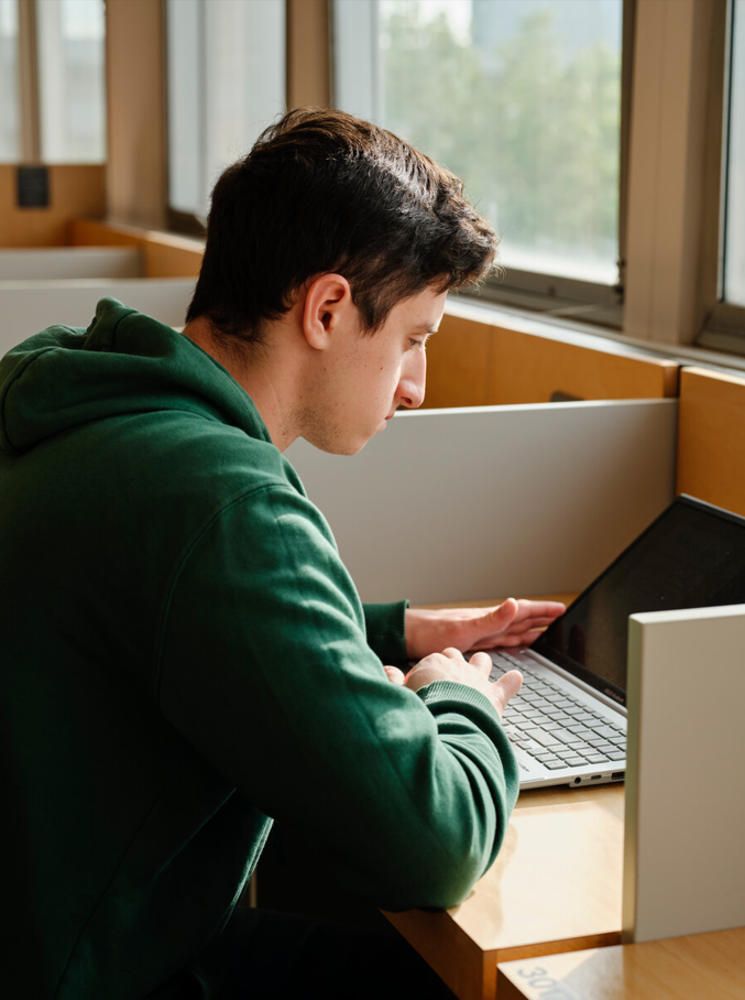 male student searching on a laptop in the library
