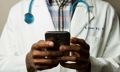 A doctor typing on a mobile phone