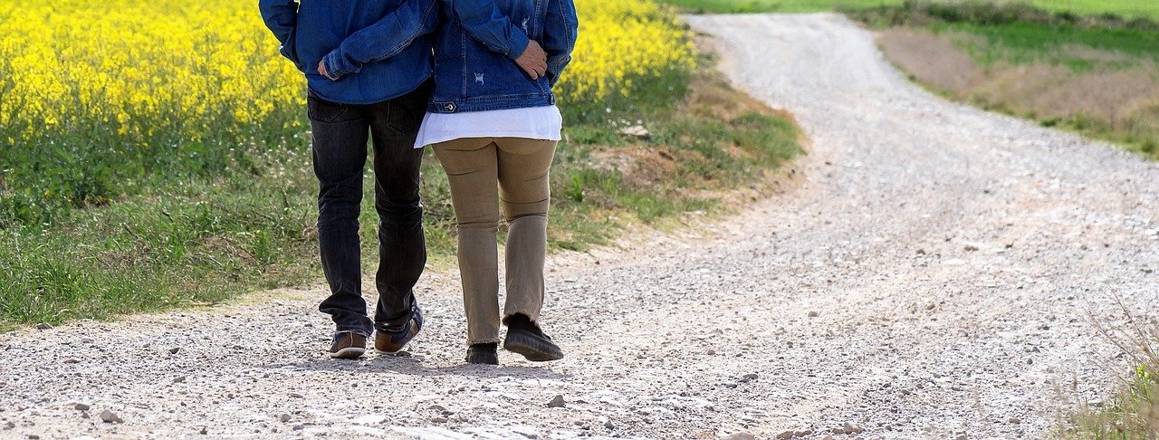 2 people walking arm in arm down a winding road