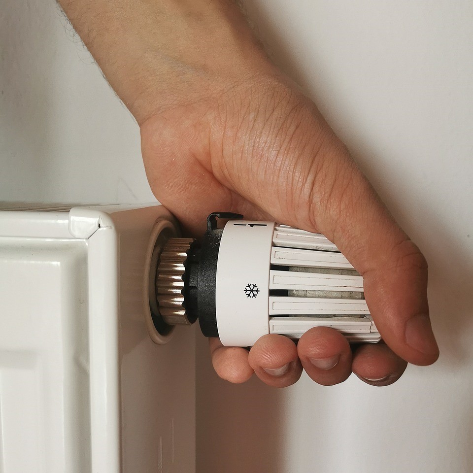 A person twisting the knob on a radiator