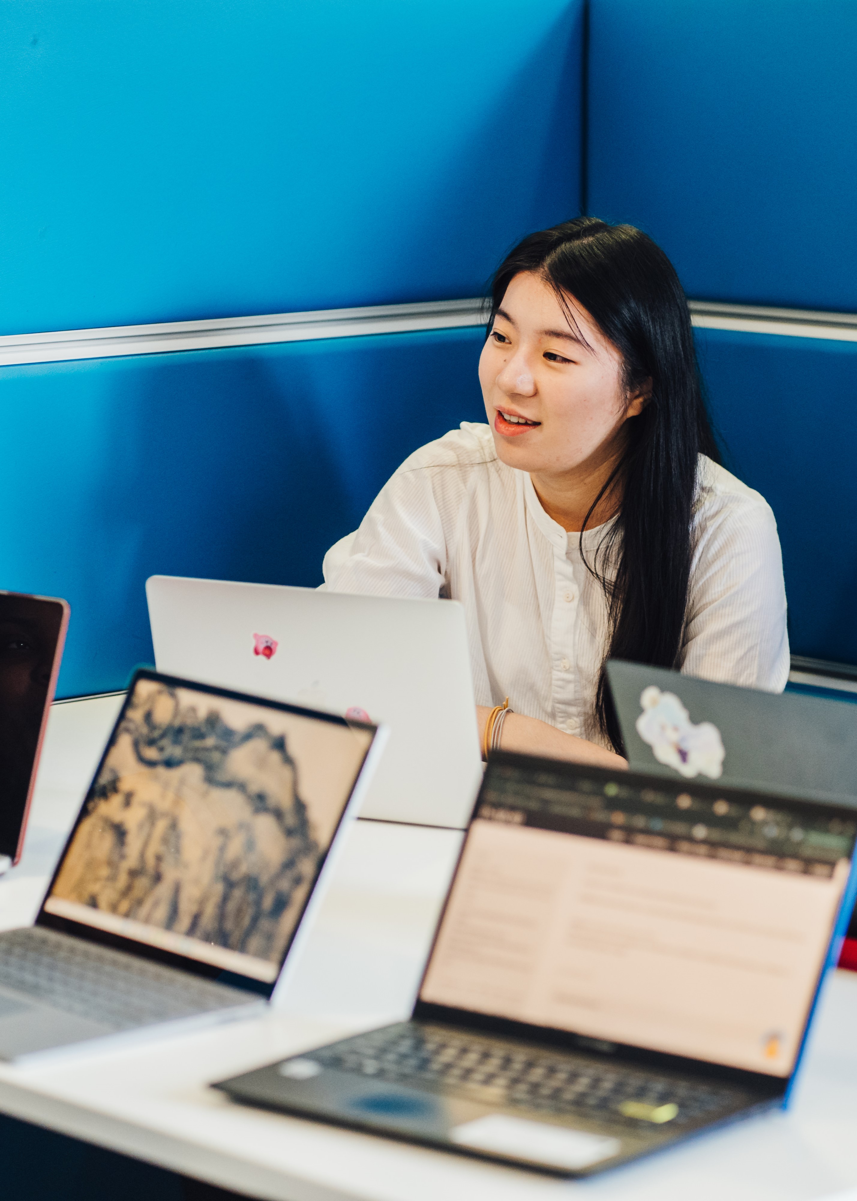 Student in discussion surrounded by various laptops