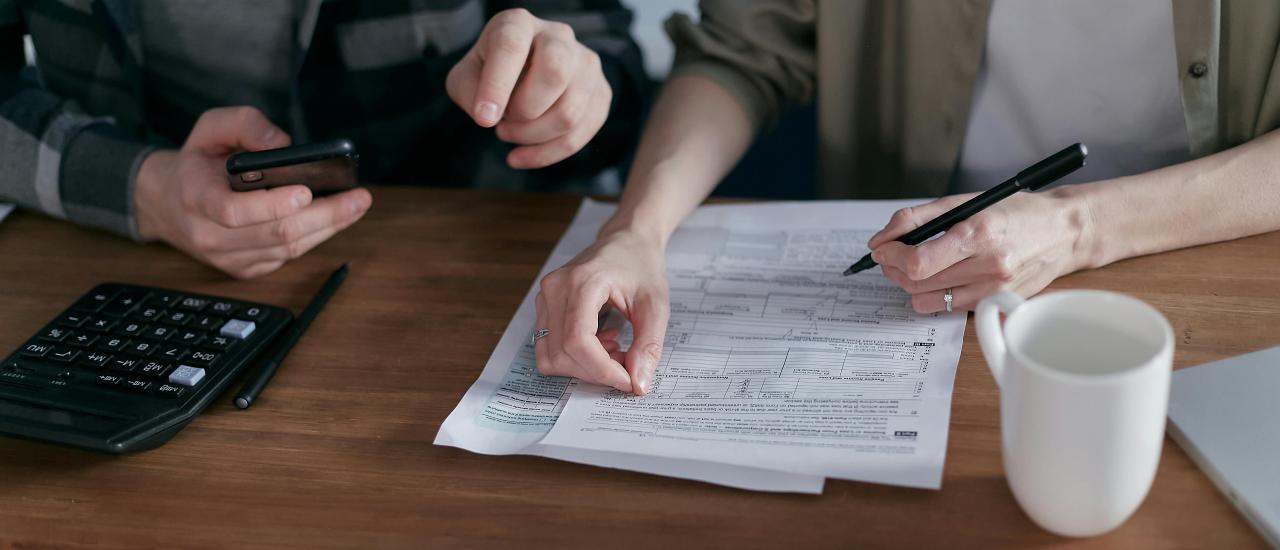 Image showing 2 people at a desk, using a calculator and a phone to fill in some paperwork
