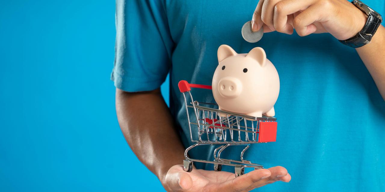 Image of a man in a blue top putting a coin in a small piggy bank balanced on a miniature trolley