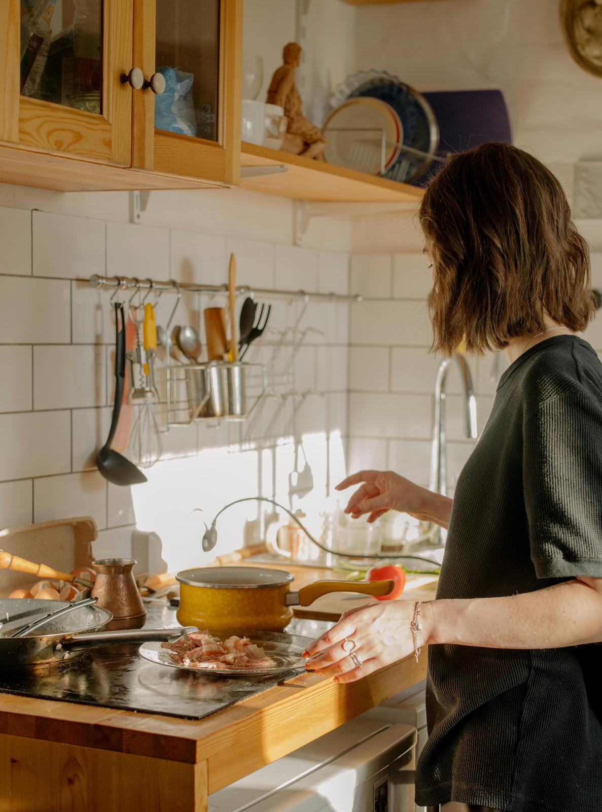 Someone cooking at a stove in a small kitchenette 