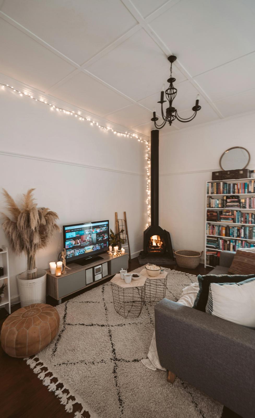 Image of a living room with a log burner, tv and tv unit and grey couch