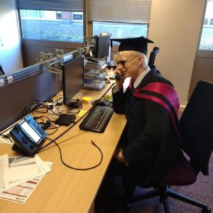 rob seated at a desk with cap and gown