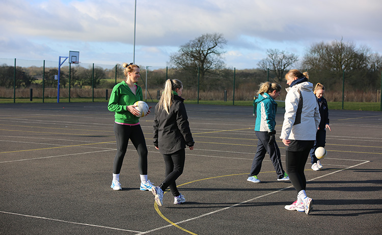 A group playing netball on an outdoor court.
