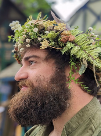 close up of a man wearing a flower crown