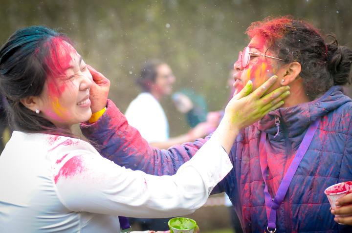 Two students smear colour powder on each other's faces