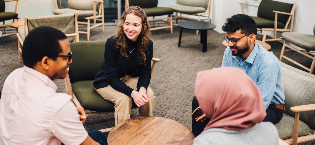 A group of students sit talking around a coffee table.